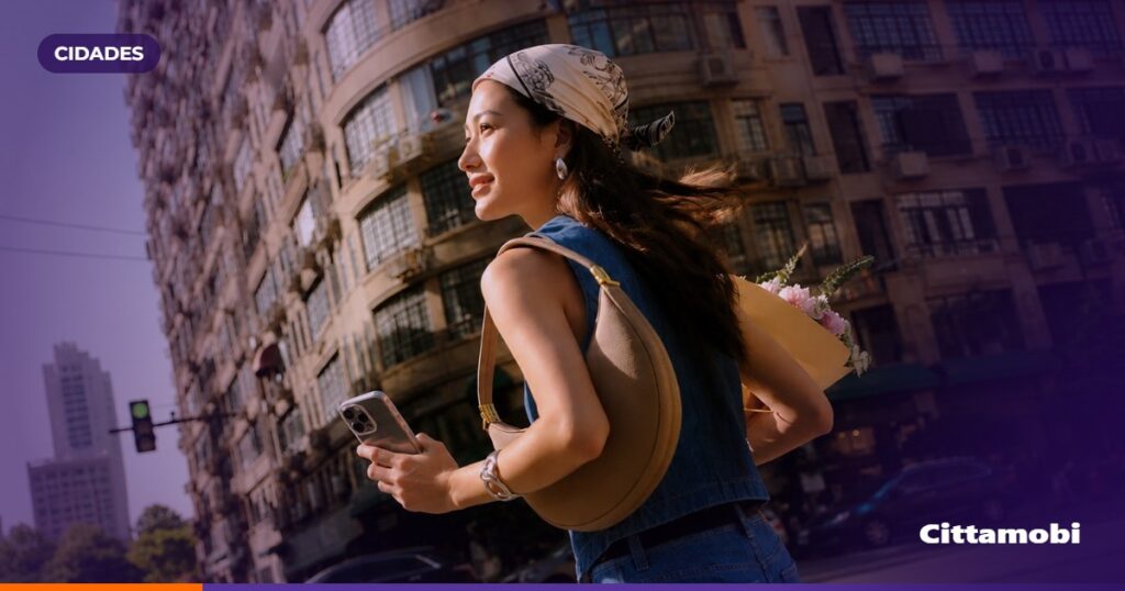Pessoas em um ponto de São Paulo observam a chegada de um ônibus enquanto consultam o celular